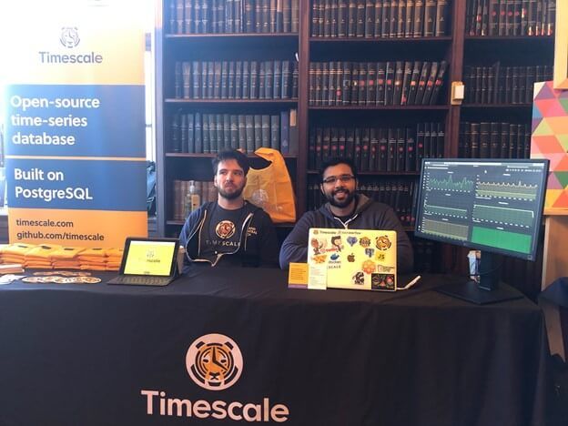 Two Timescale team members sit at table demo'ing Grafana + Prometheus + TimescaleDB