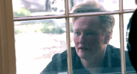 Comedian Conan O'Brien looking inside a house through its window